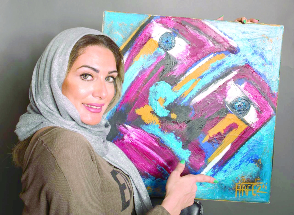 التشكيلية غدير مع إحدى لوحاتها