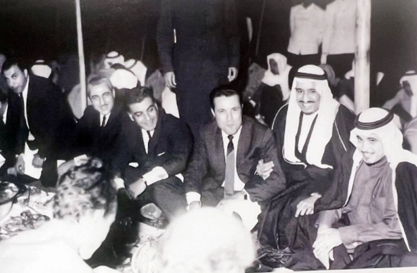 الملك سلمان في إحدى المناسبات الرياضية وإلى يساره العنقري